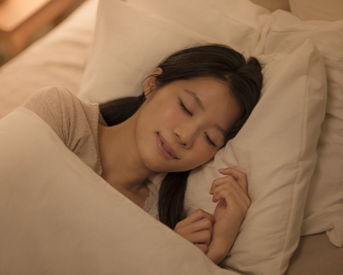 写真：ベッドでぐっすり眠っている様子の女性
