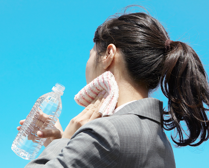 写真：汗をかいて水分補給をしている女性の後ろ姿